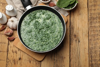 Photo of Delicious spinach sauce served on wooden table, flat lay