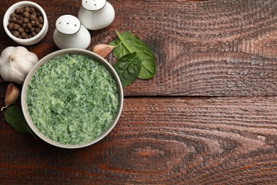 Photo of Delicious spinach sauce served on wooden table, flat lay. Space for text