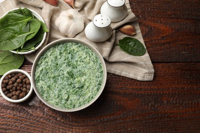 Photo of Delicious spinach sauce served on wooden table, flat lay. Space for text