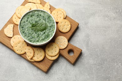 Photo of Delicious spinach sauce served with crackers on grey table, top view. Space for text