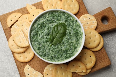 Photo of Delicious spinach sauce served with crackers on grey table, top view