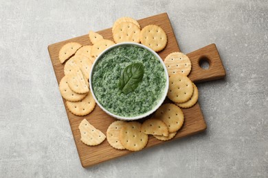 Photo of Delicious spinach sauce served with crackers on grey table, top view