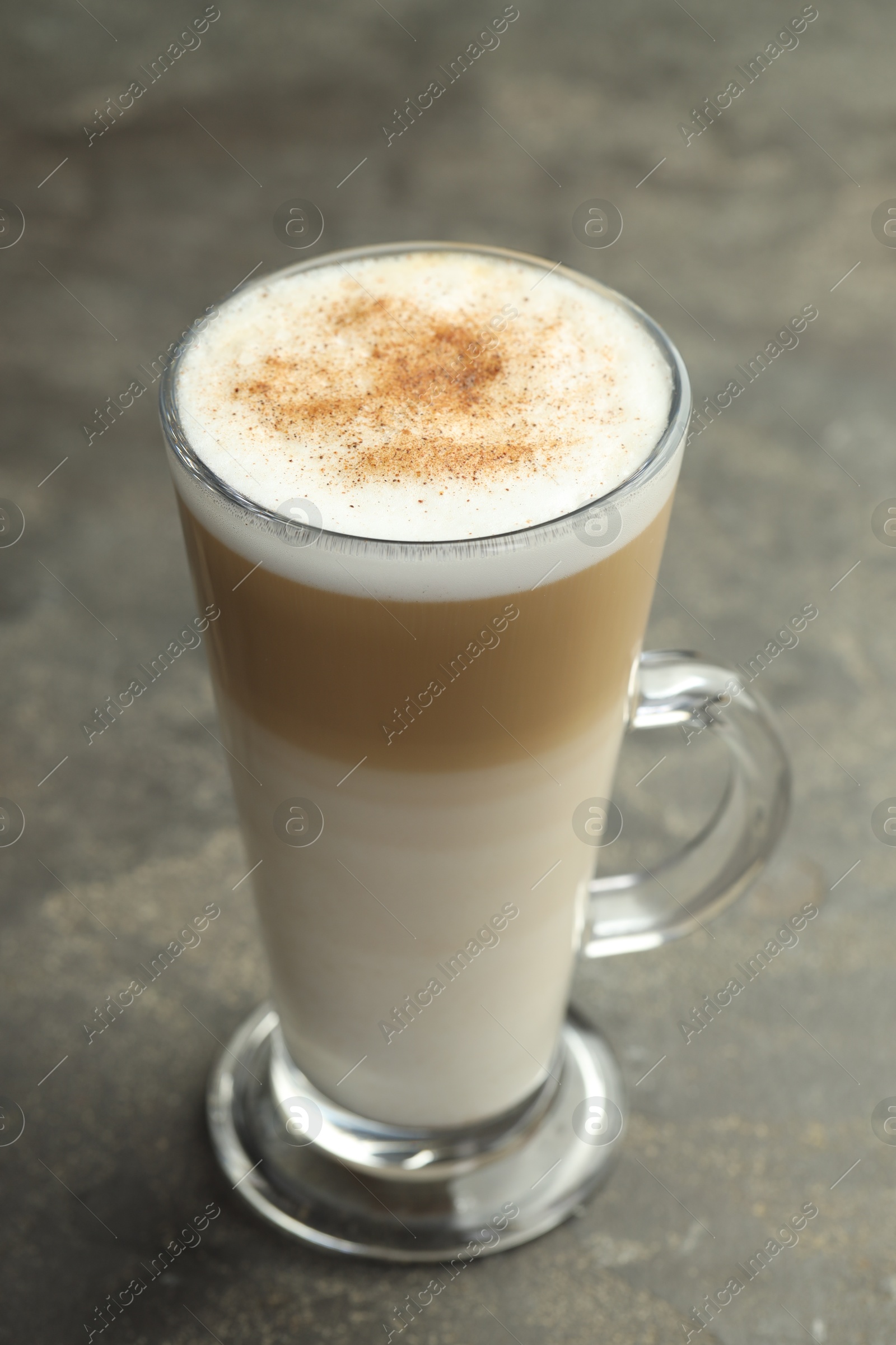 Photo of Tasty latte macchiato in glass cup on grey table, closeup