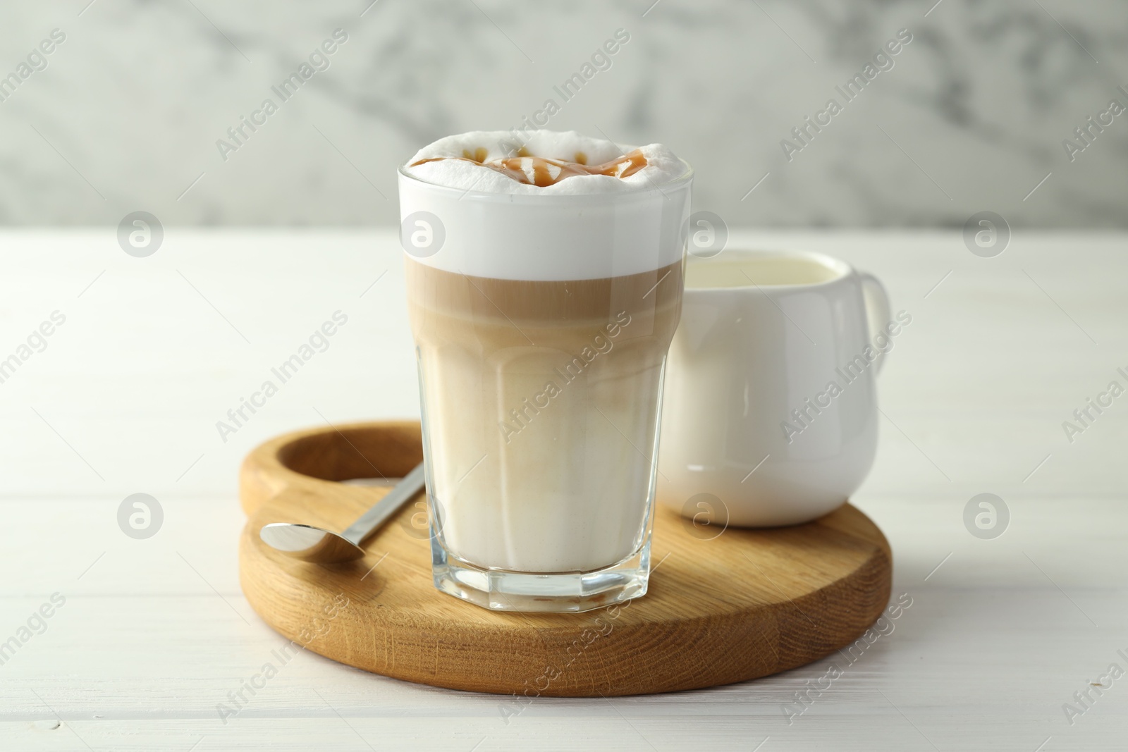 Photo of Tasty latte macchiato in glass on white wooden table, closeup