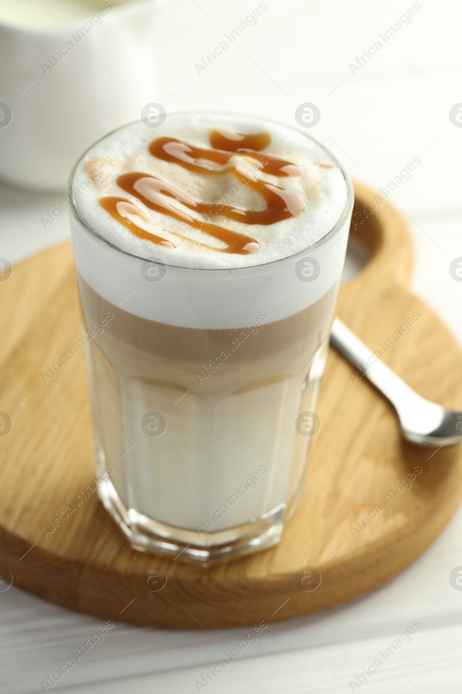 Photo of Tasty latte macchiato in glass on white wooden table, closeup