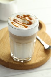 Photo of Tasty latte macchiato in glass on white wooden table, closeup