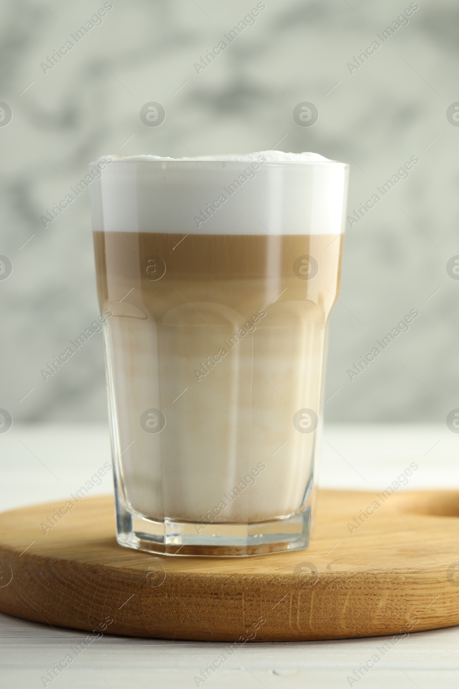 Photo of Tasty latte macchiato in glass on white wooden table, closeup