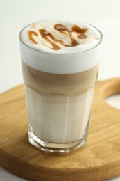 Photo of Tasty latte macchiato in glass on white wooden table, closeup