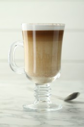 Photo of Tasty latte macchiato in glass cup on white marble table, closeup