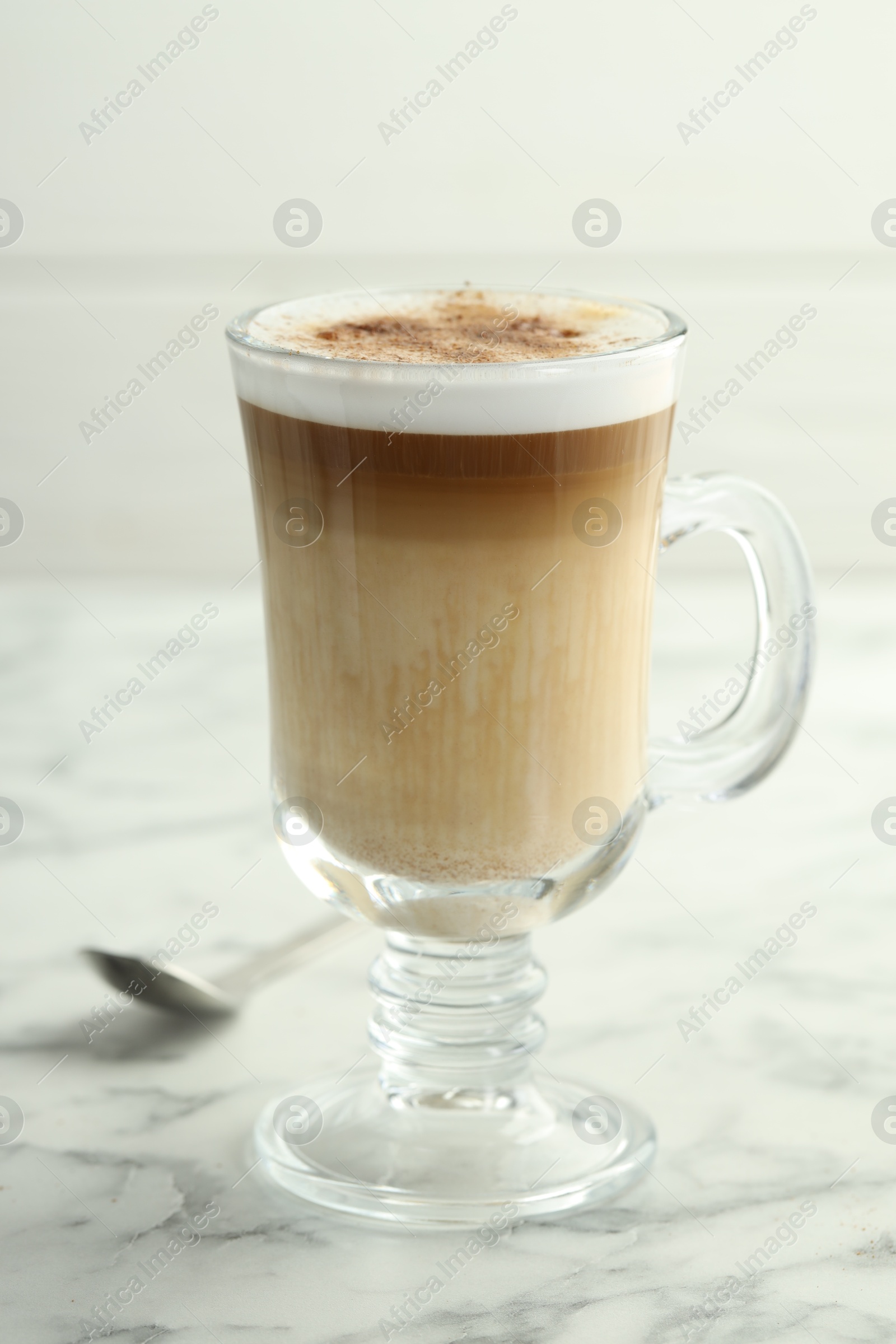 Photo of Tasty latte macchiato in glass cup on white marble table, closeup