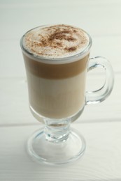 Photo of Tasty latte macchiato in glass cup on white wooden table, closeup