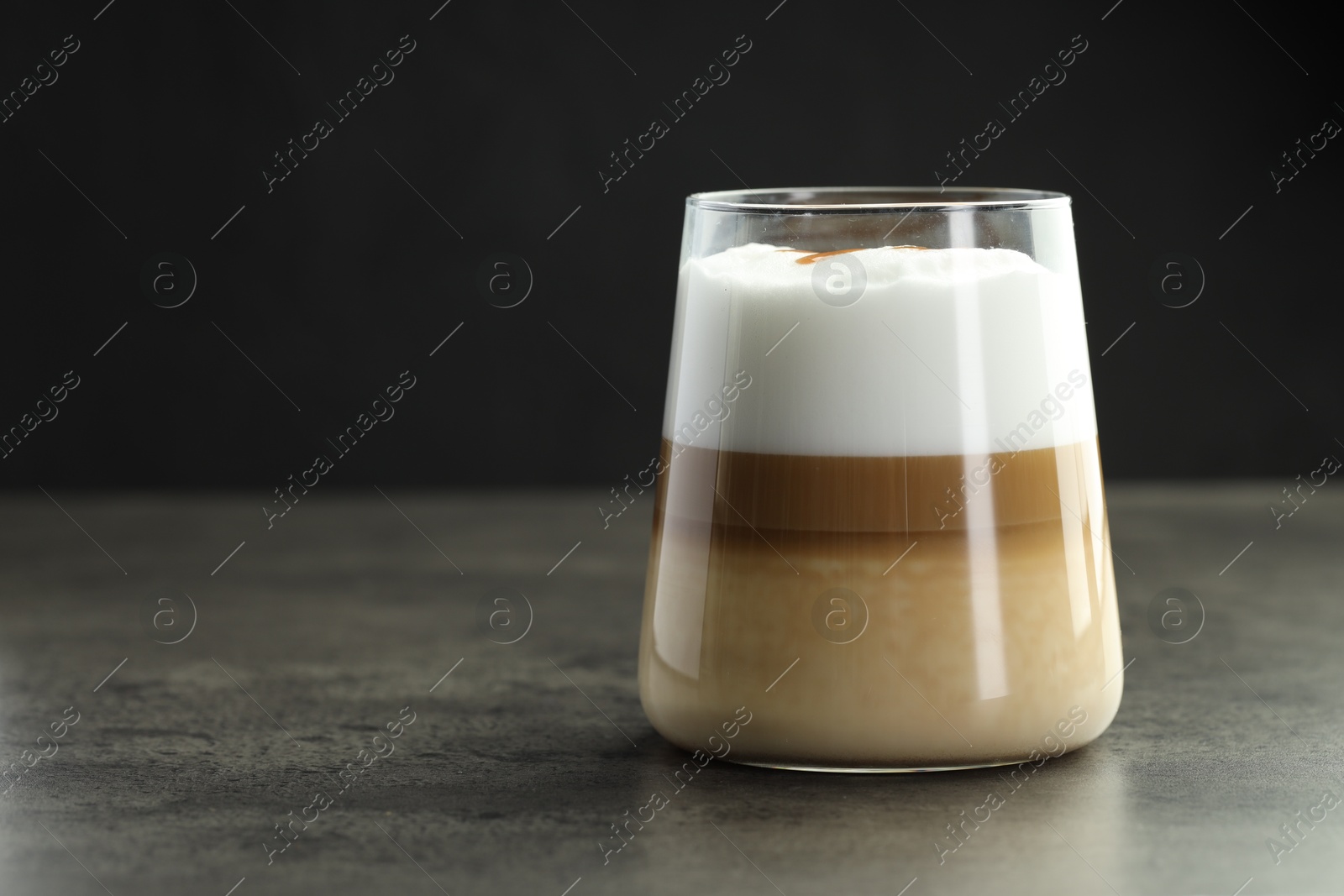 Photo of Tasty latte macchiato in glass on grey table, closeup. Space for text