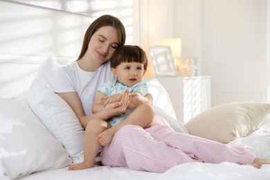 Photo of Mother with her little son on bed at home