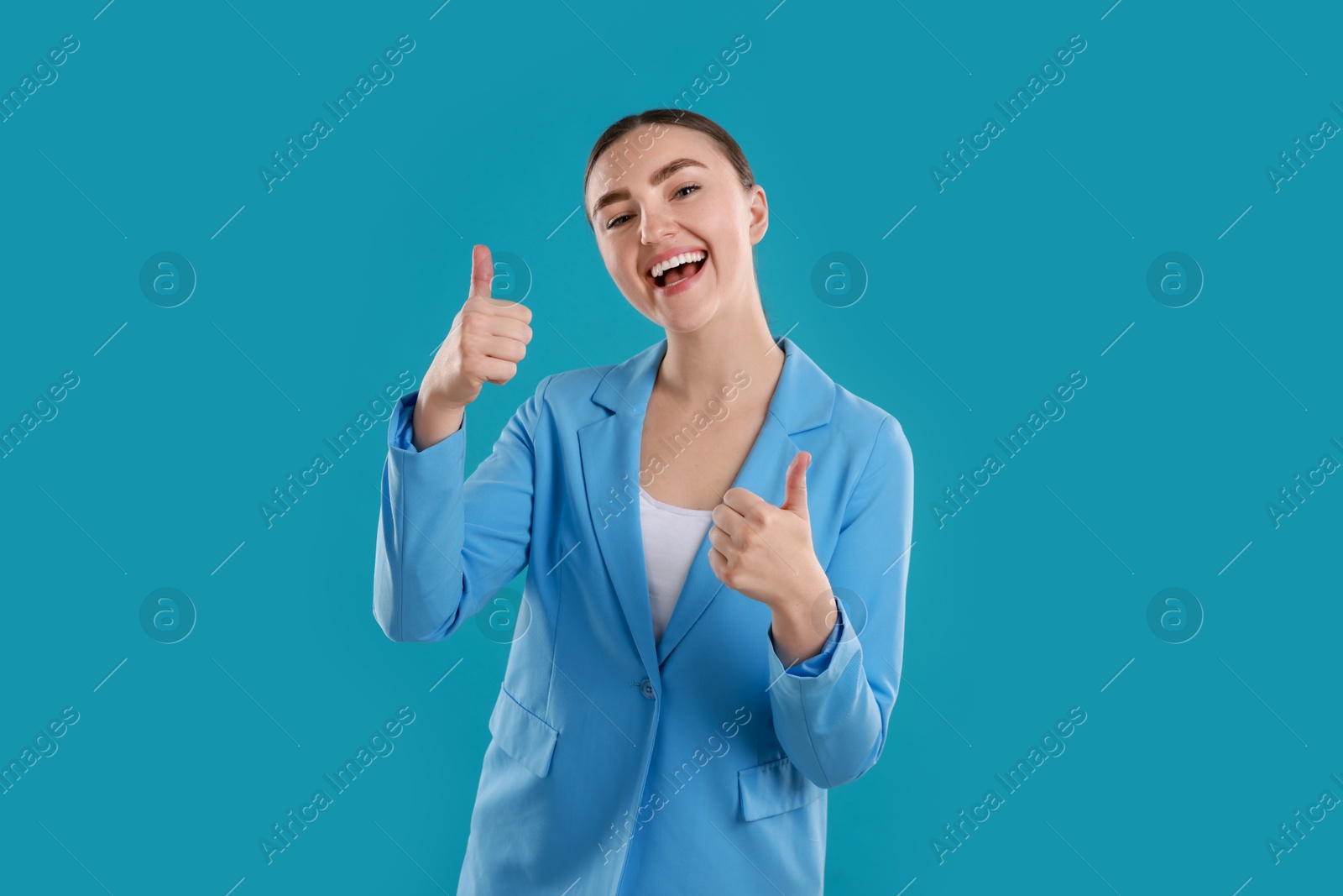 Photo of Happy woman showing thumbs up on light blue background. Like gesture