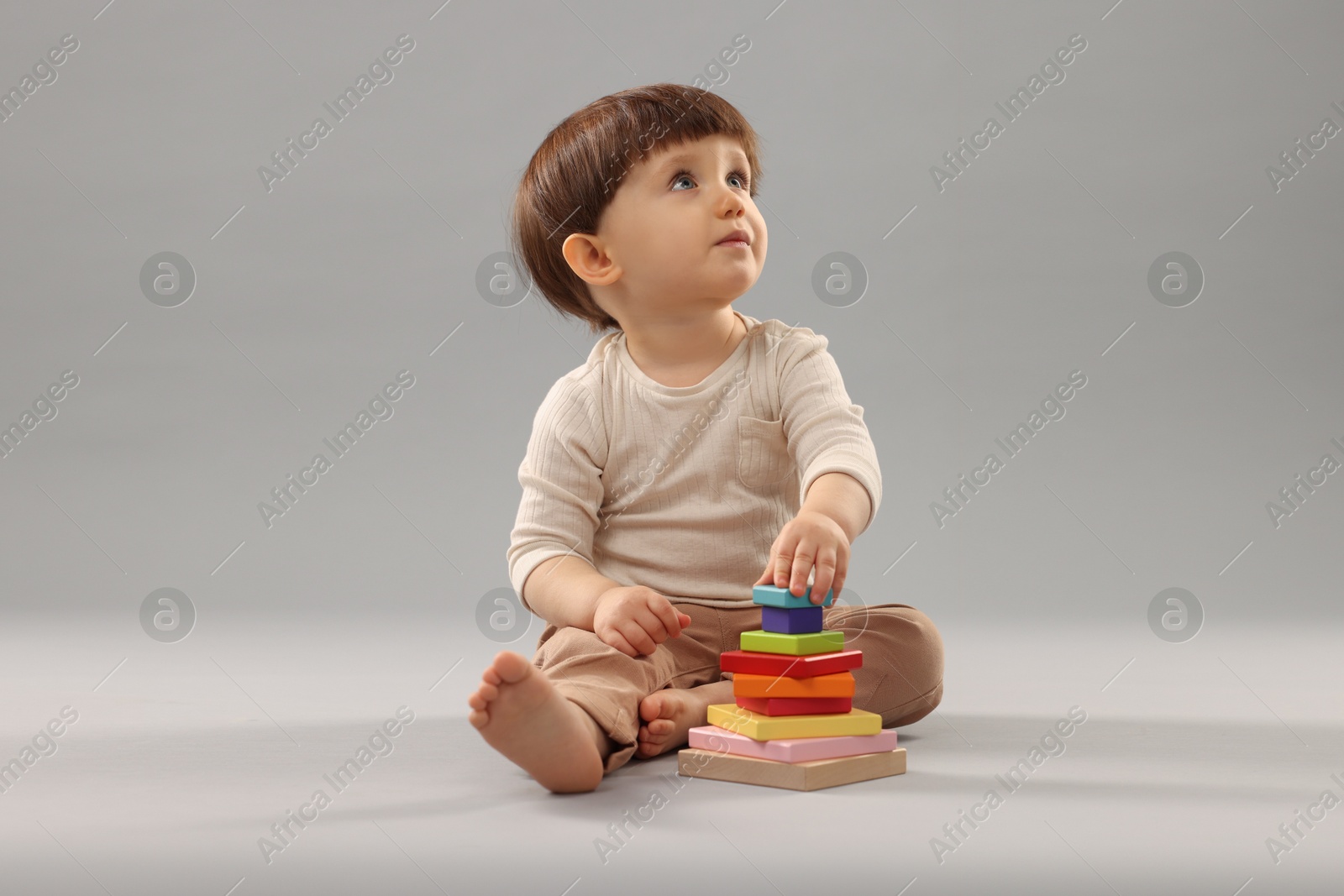 Photo of Cute little boy playing on grey background