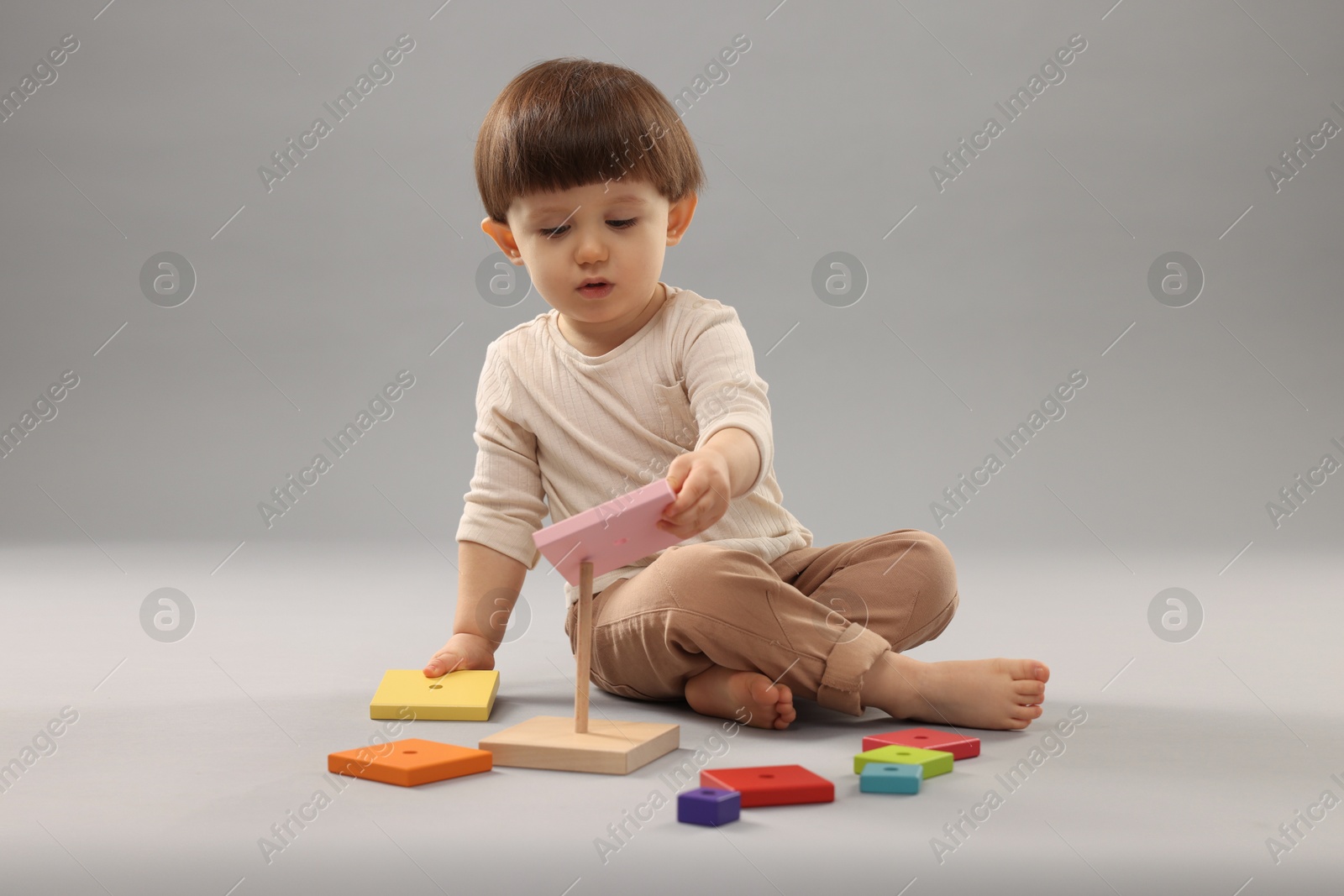 Photo of Cute little boy playing on grey background