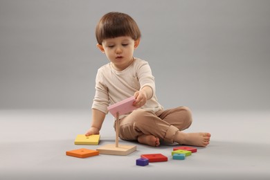 Photo of Cute little boy playing on grey background