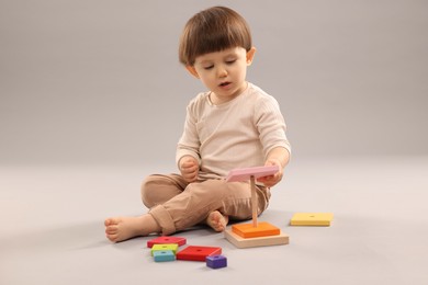 Photo of Cute little boy playing on grey background