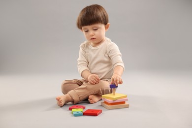 Photo of Cute little boy playing on grey background