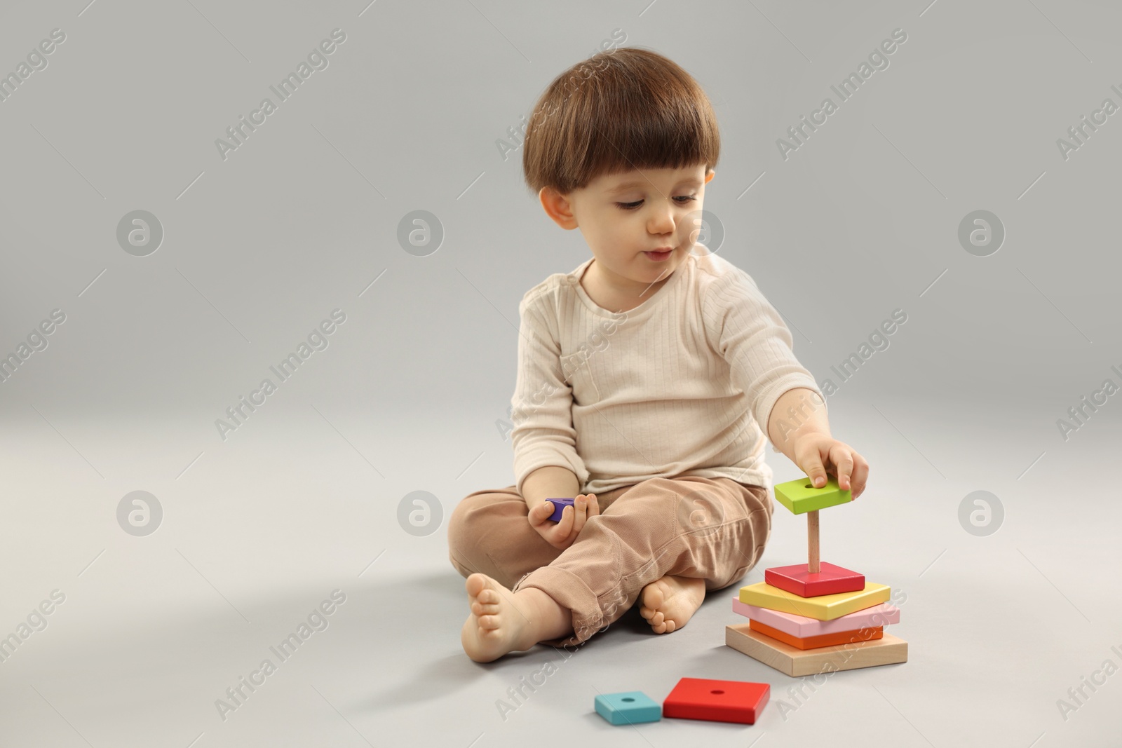 Photo of Cute little boy playing on grey background. Space for text