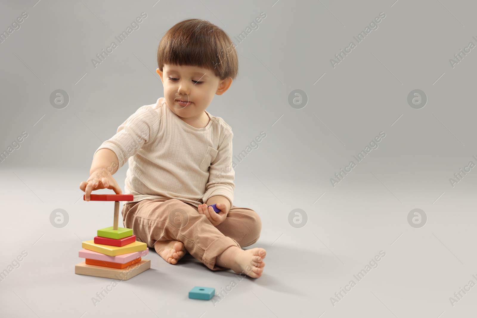 Photo of Cute little boy playing on grey background. Space for text