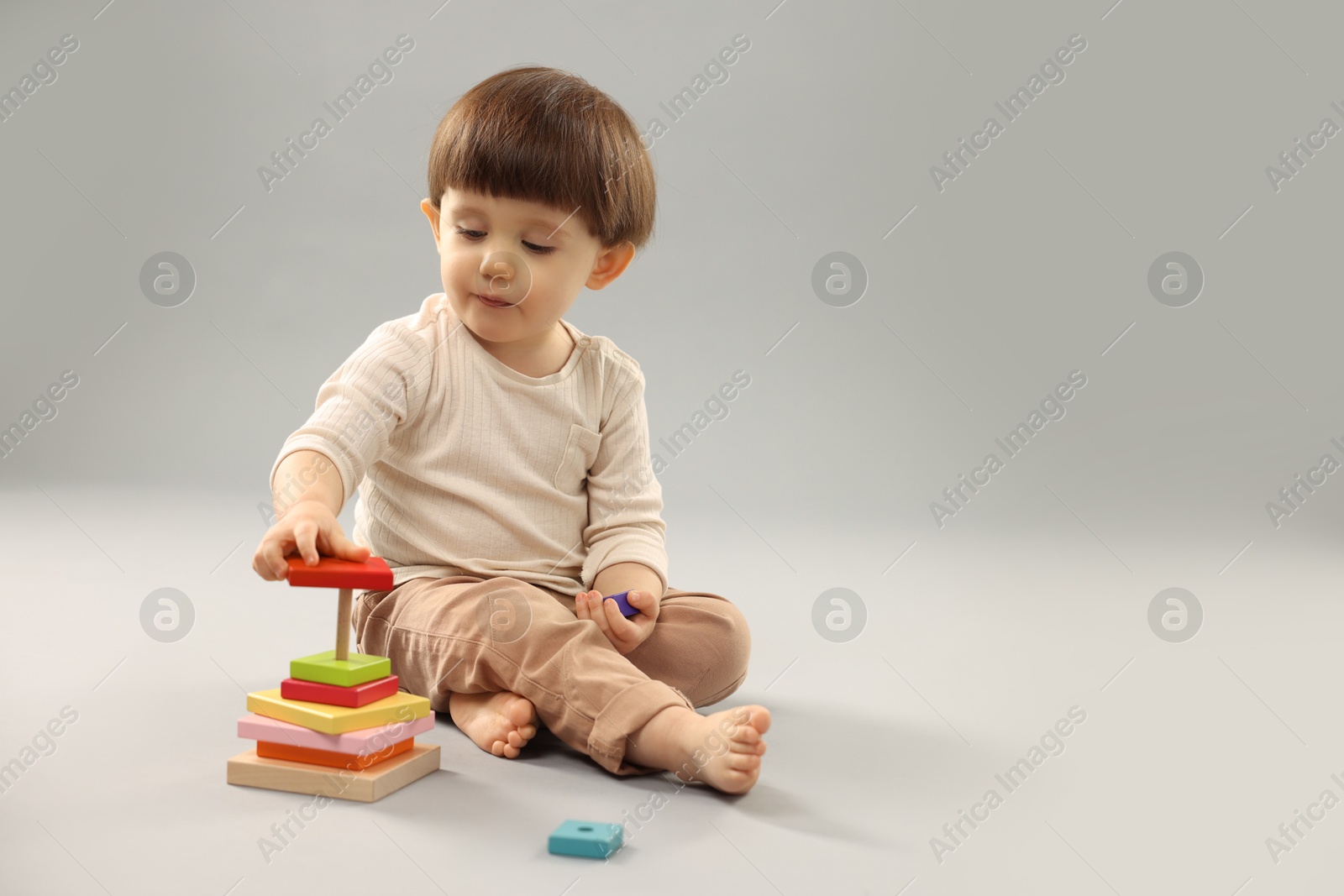 Photo of Cute little boy playing on grey background. Space for text