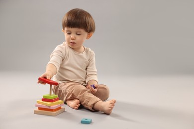 Photo of Cute little boy playing on grey background. Space for text