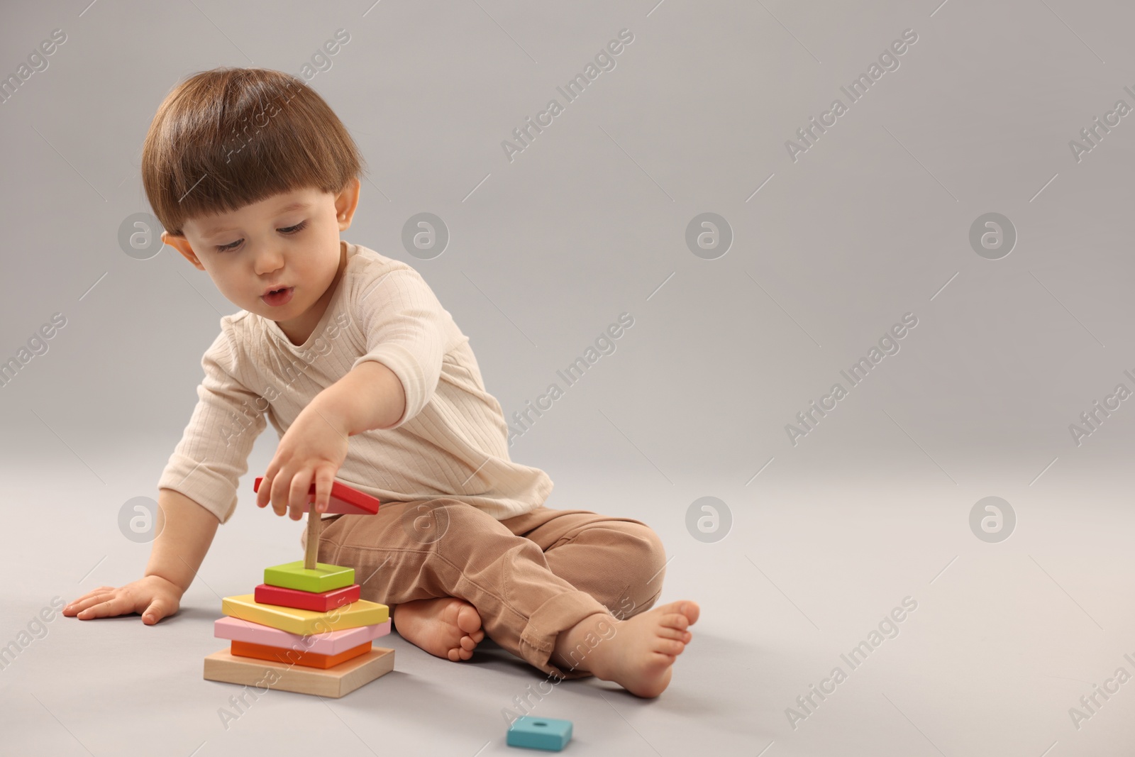 Photo of Cute little boy playing on grey background. Space for text