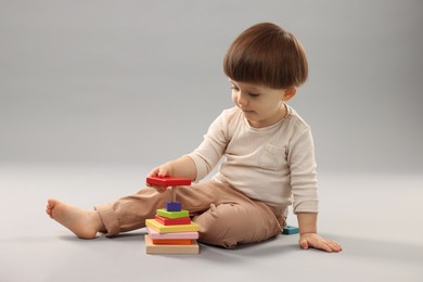 Photo of Cute little boy playing on grey background