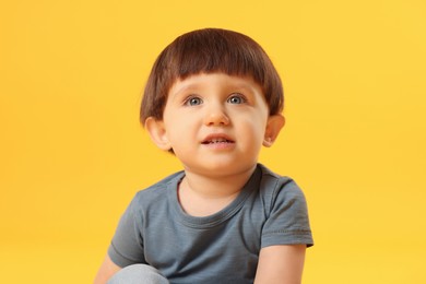 Photo of Portrait of cute little boy on yellow background. Space for text