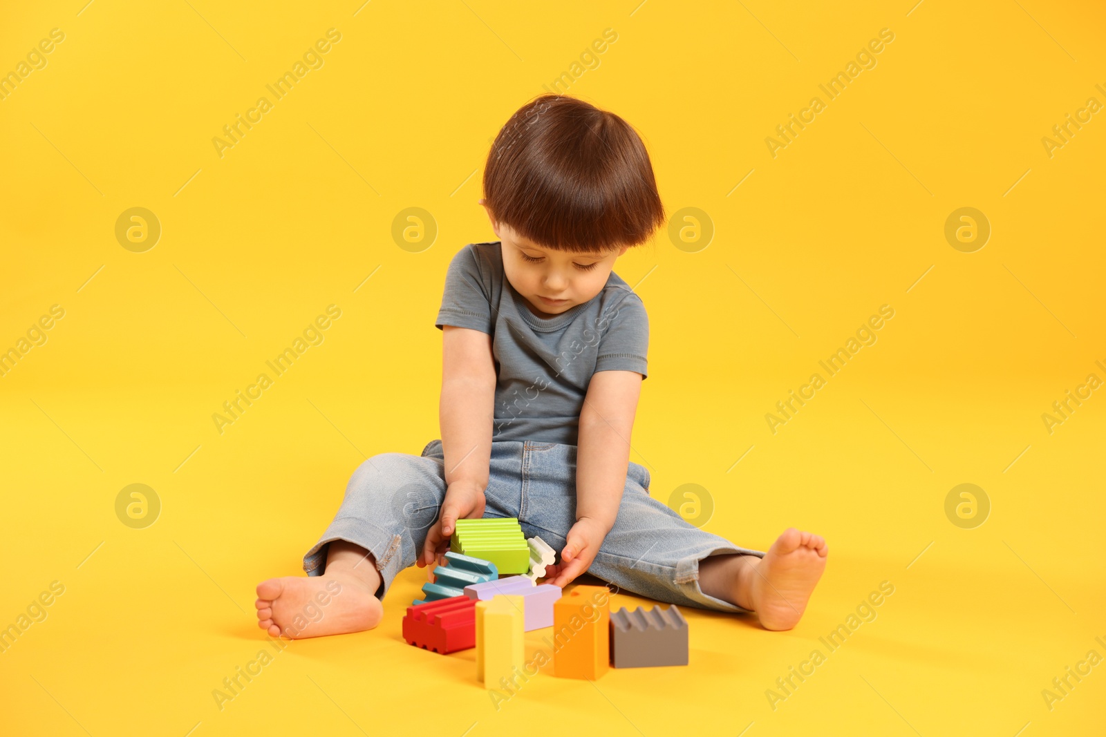 Photo of Cute little boy playing on yellow background