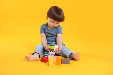 Photo of Cute little boy playing on yellow background