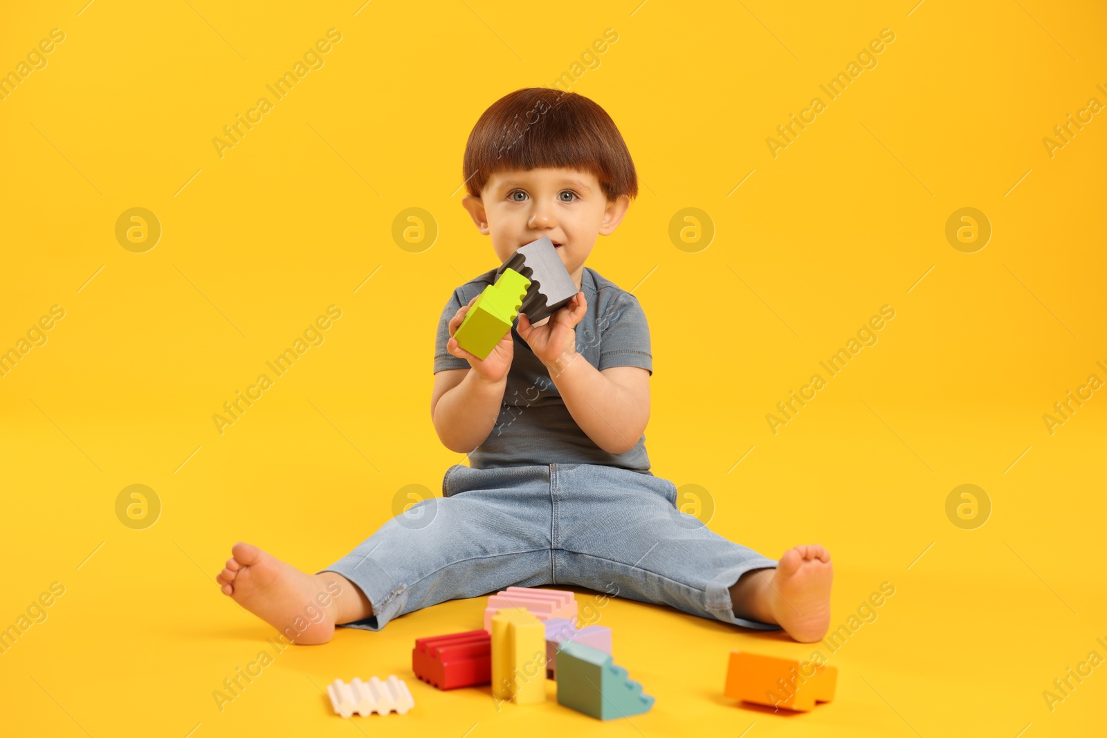 Photo of Cute little boy playing on yellow background