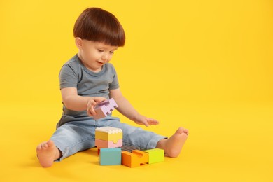 Photo of Cute little boy playing on yellow background. Space for text