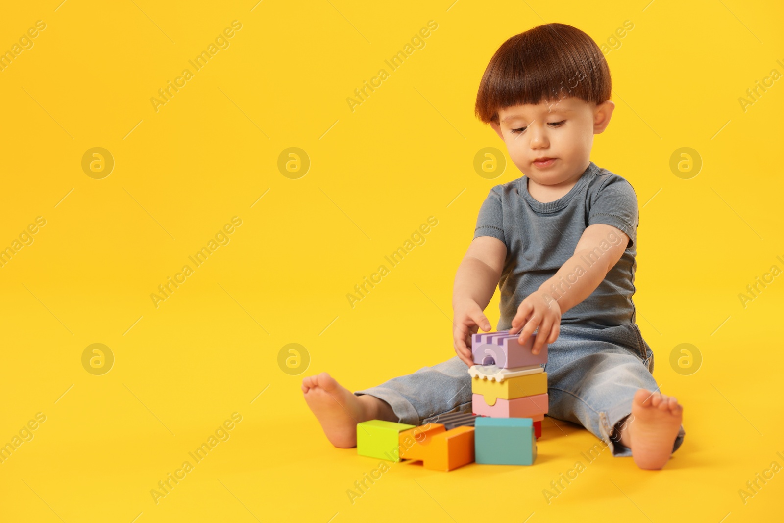 Photo of Cute little boy playing on yellow background. Space for text