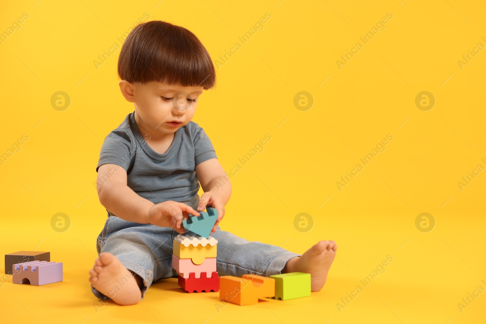 Photo of Cute little boy playing on yellow background. Space for text