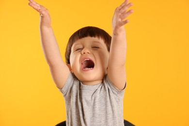 Photo of Portrait of emotional little boy on yellow background