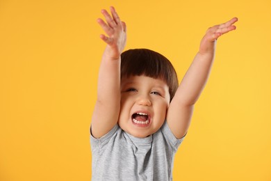 Photo of Portrait of emotional little boy on yellow background