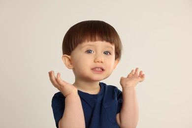 Photo of Portrait of cute little boy on light grey background