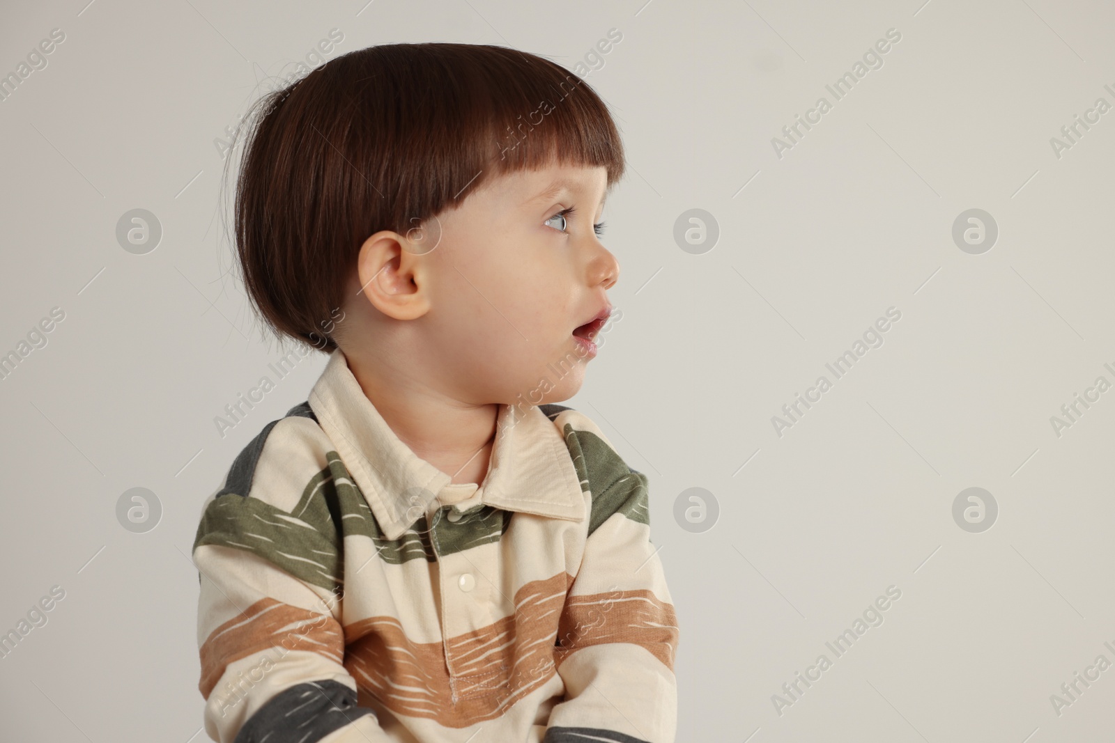 Photo of Cute little boy on light grey background. Space for text