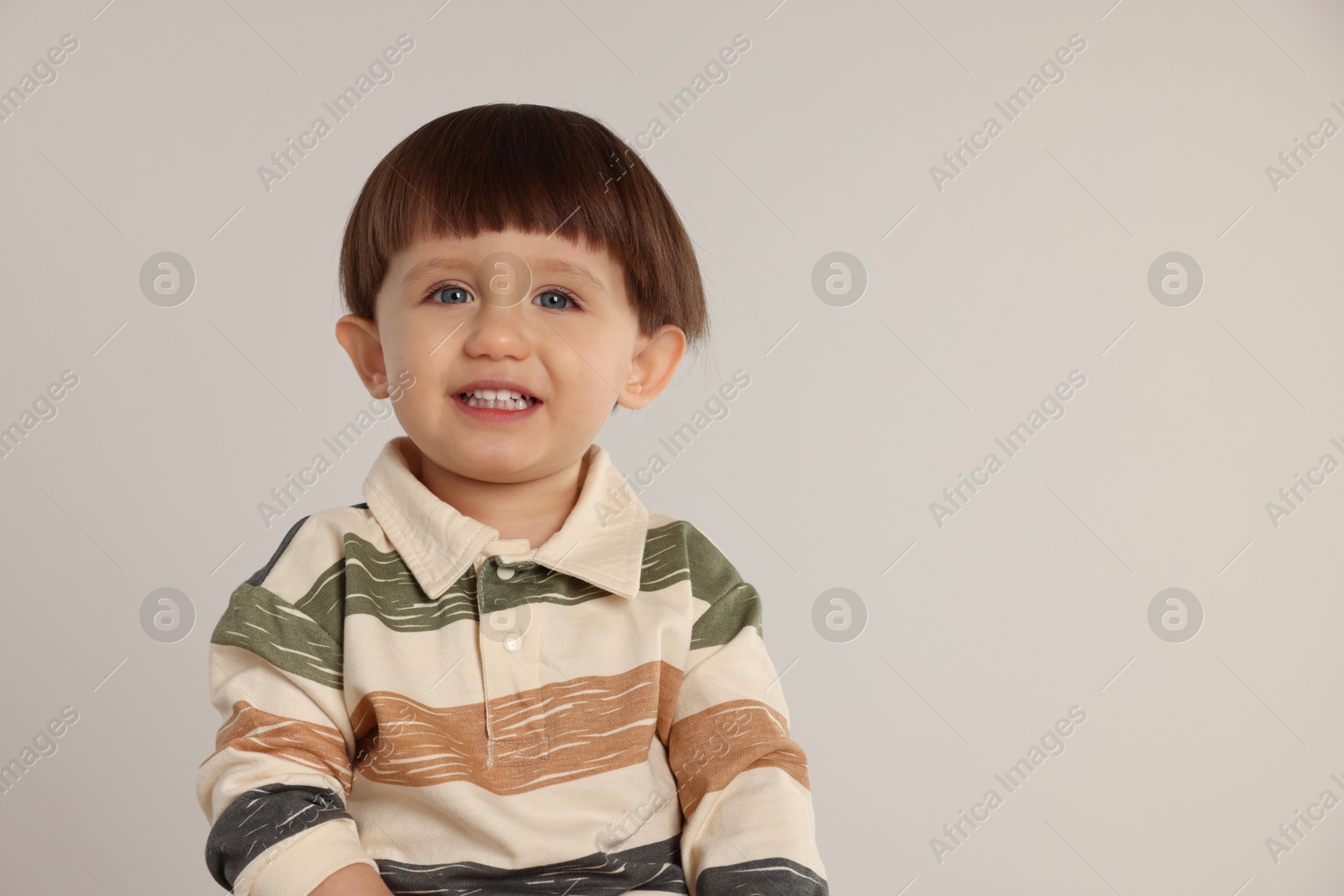 Photo of Portrait of happy little boy on light grey background. Space for text