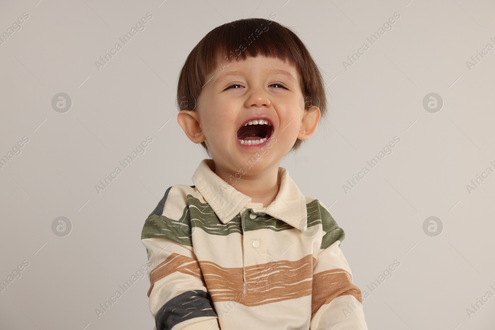 Photo of Portrait of emotional little boy on light grey background