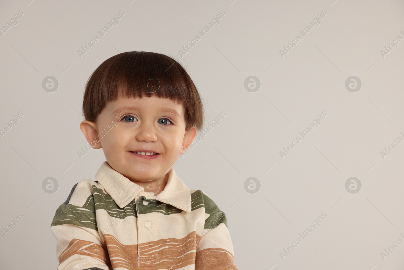 Photo of Portrait of happy little boy on light grey background. Space for text