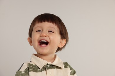 Photo of Portrait of happy little boy on light grey background. Space for text