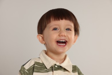 Photo of Portrait of happy little boy on light grey background