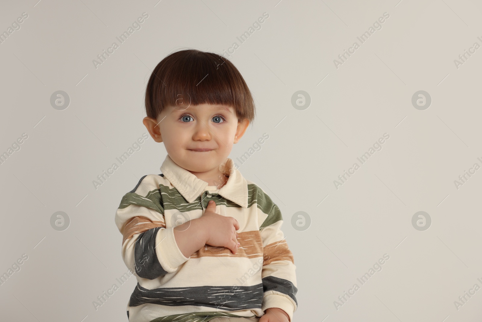 Photo of Cute little boy on light grey background. Space for text