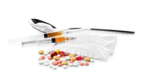 Photo of Drug addiction. Different pills, spoon with powder and syringes isolated on white