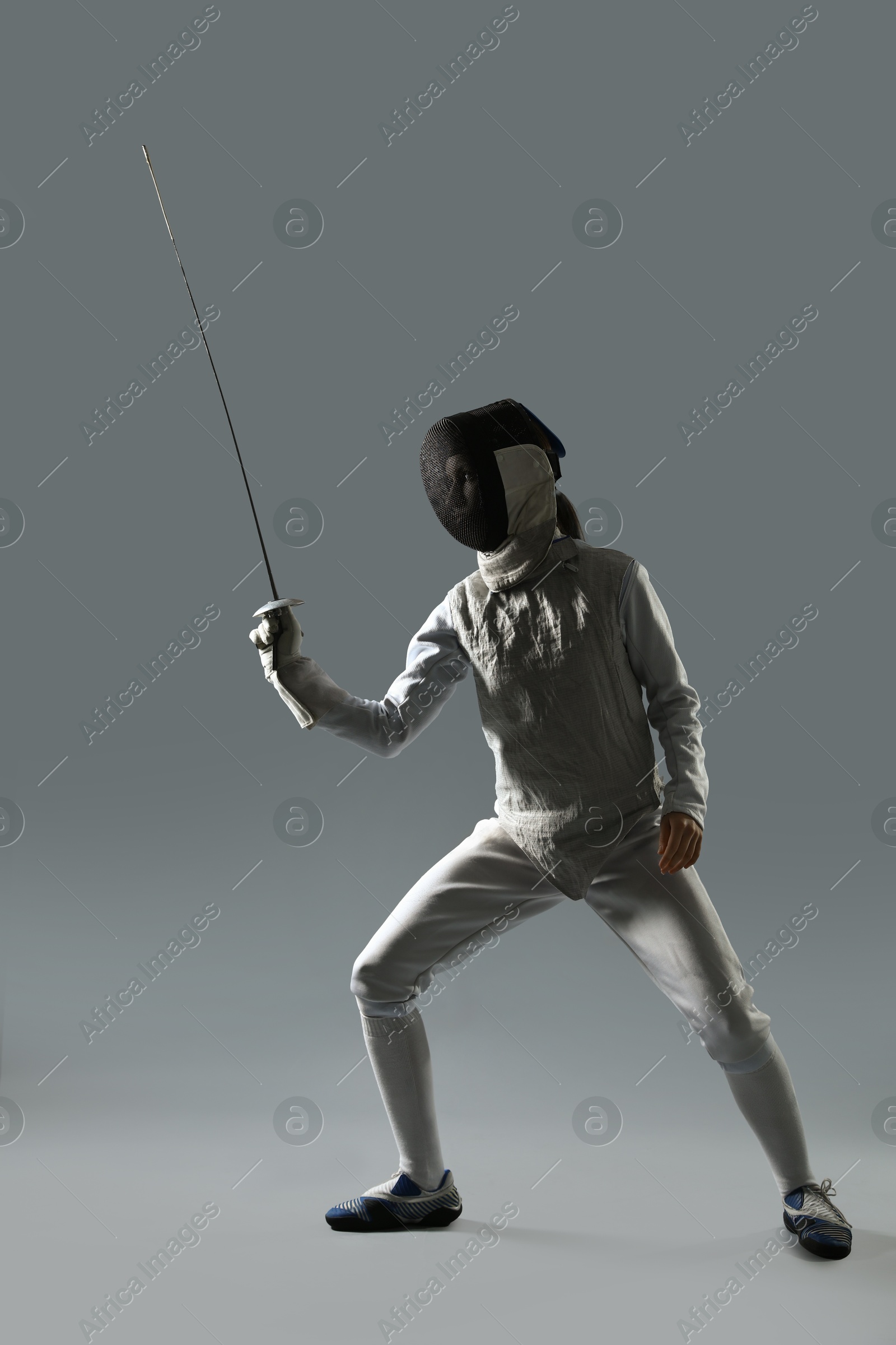 Photo of Fencer with epee practicing on gray background