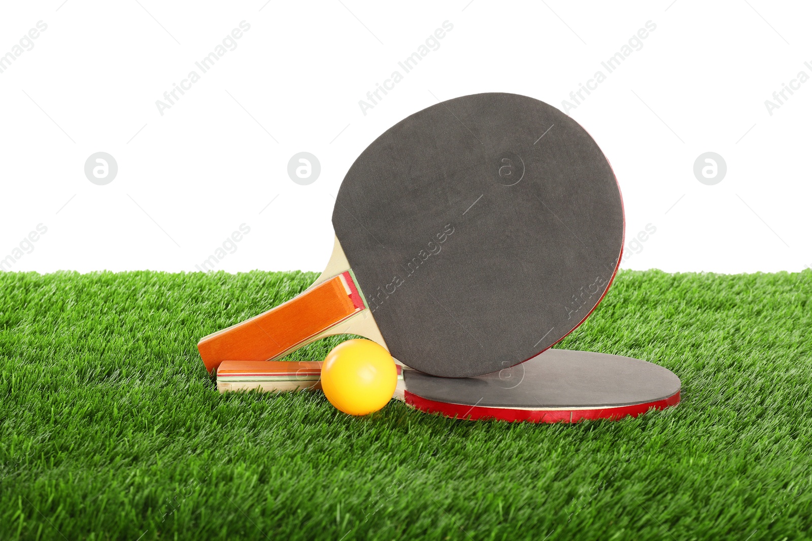 Photo of Ping pong rackets and ball on artificial grass isolated on white. Sport equipment