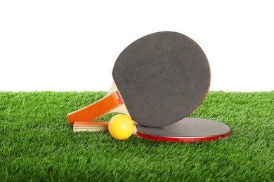 Photo of Ping pong rackets and ball on artificial grass isolated on white. Sport equipment